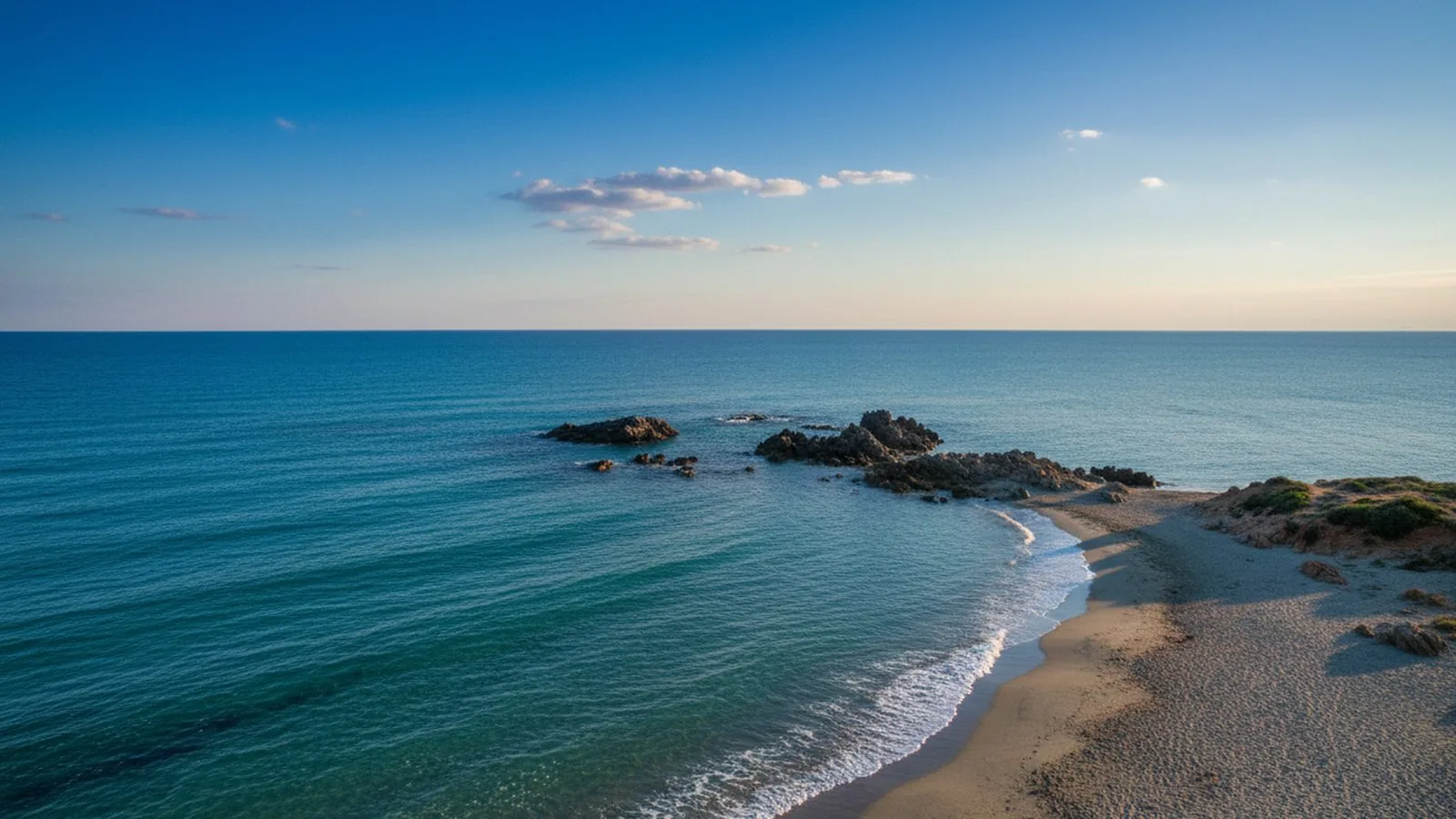 La lunga spiaggia di Colostrai con l'acqua bassa e le montagne sullo sfondo